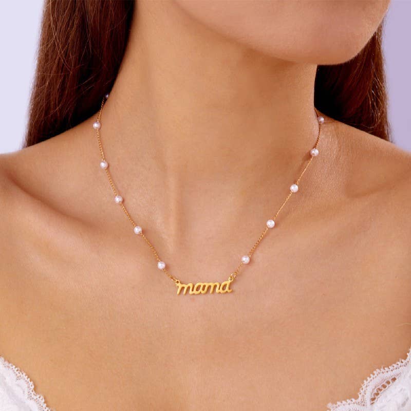 Gold necklace with 'mama' pendant and pearl accents on a model against a white background
