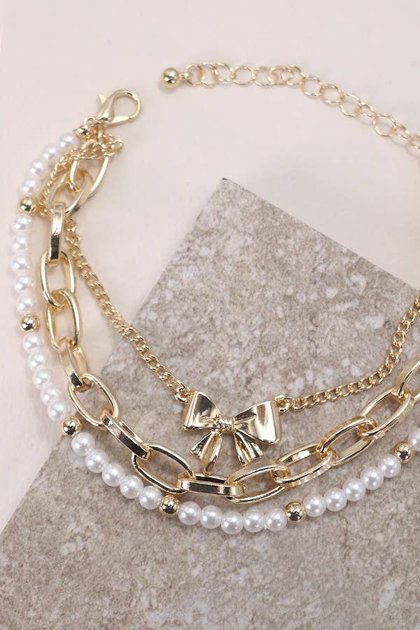 Stack of gold and pearl bracelets on a neutral background