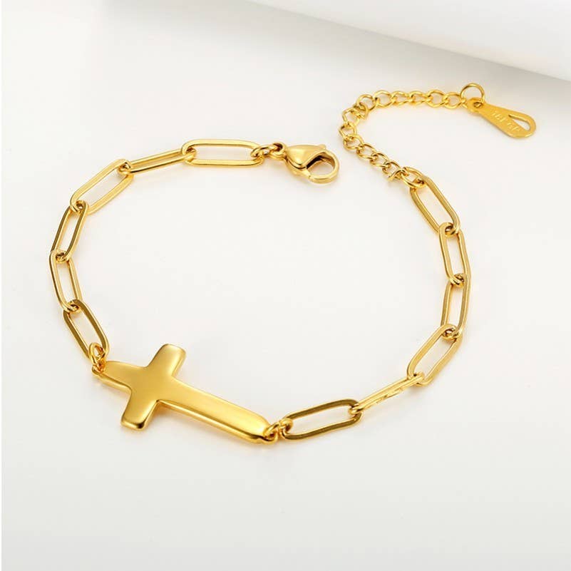 Gold chain bracelet with a cross charm on a white background