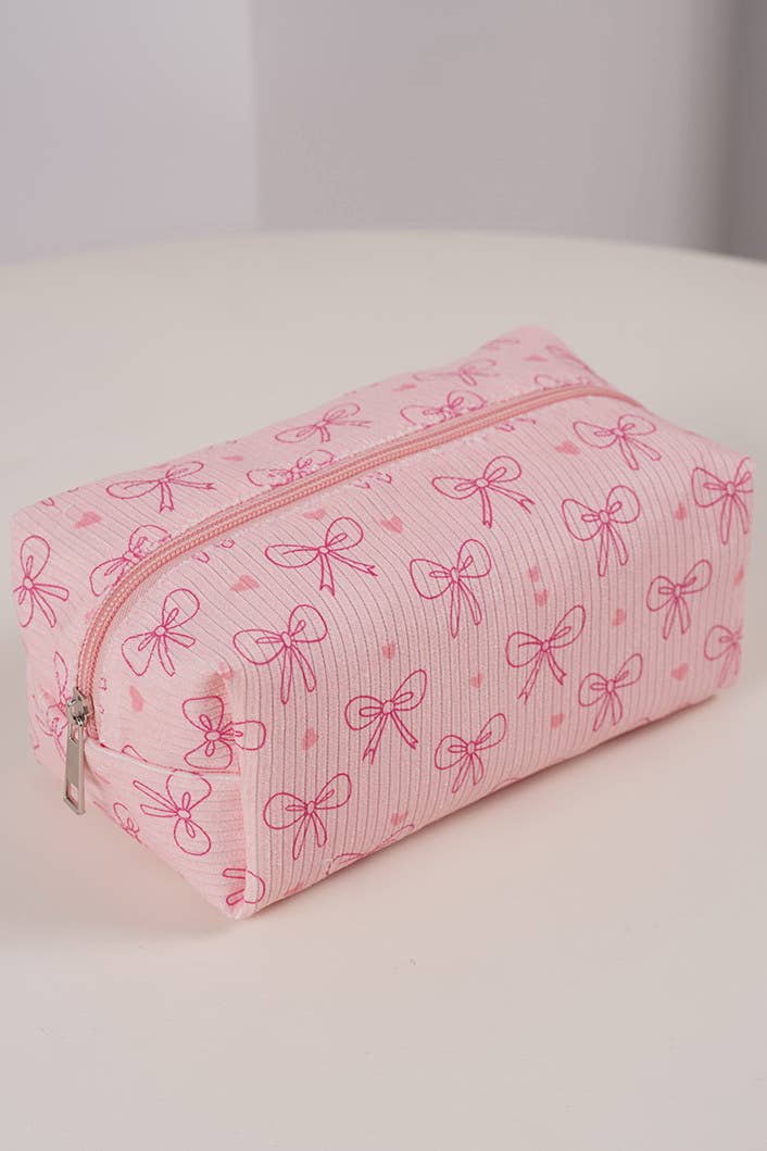 Pink cosmetic bag with bow pattern on a white surface