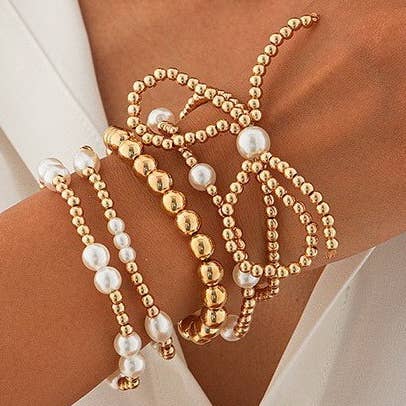 Gold and pearl beaded bracelet set on a wrist against a neutral background