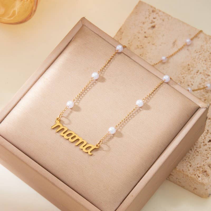 Gold necklace with 'mama' pendant on a beige box