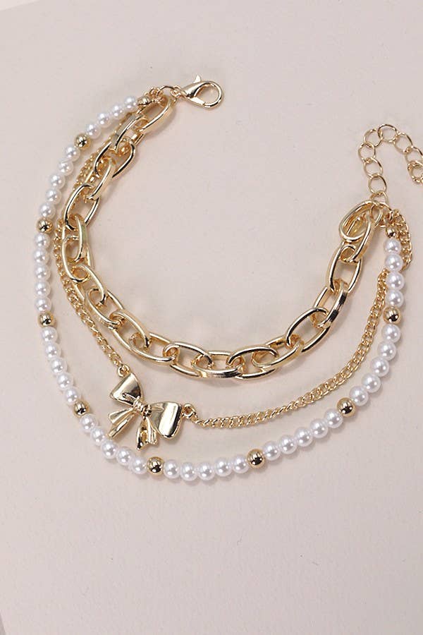 Stack of gold and pearl bracelets on a light pink background
