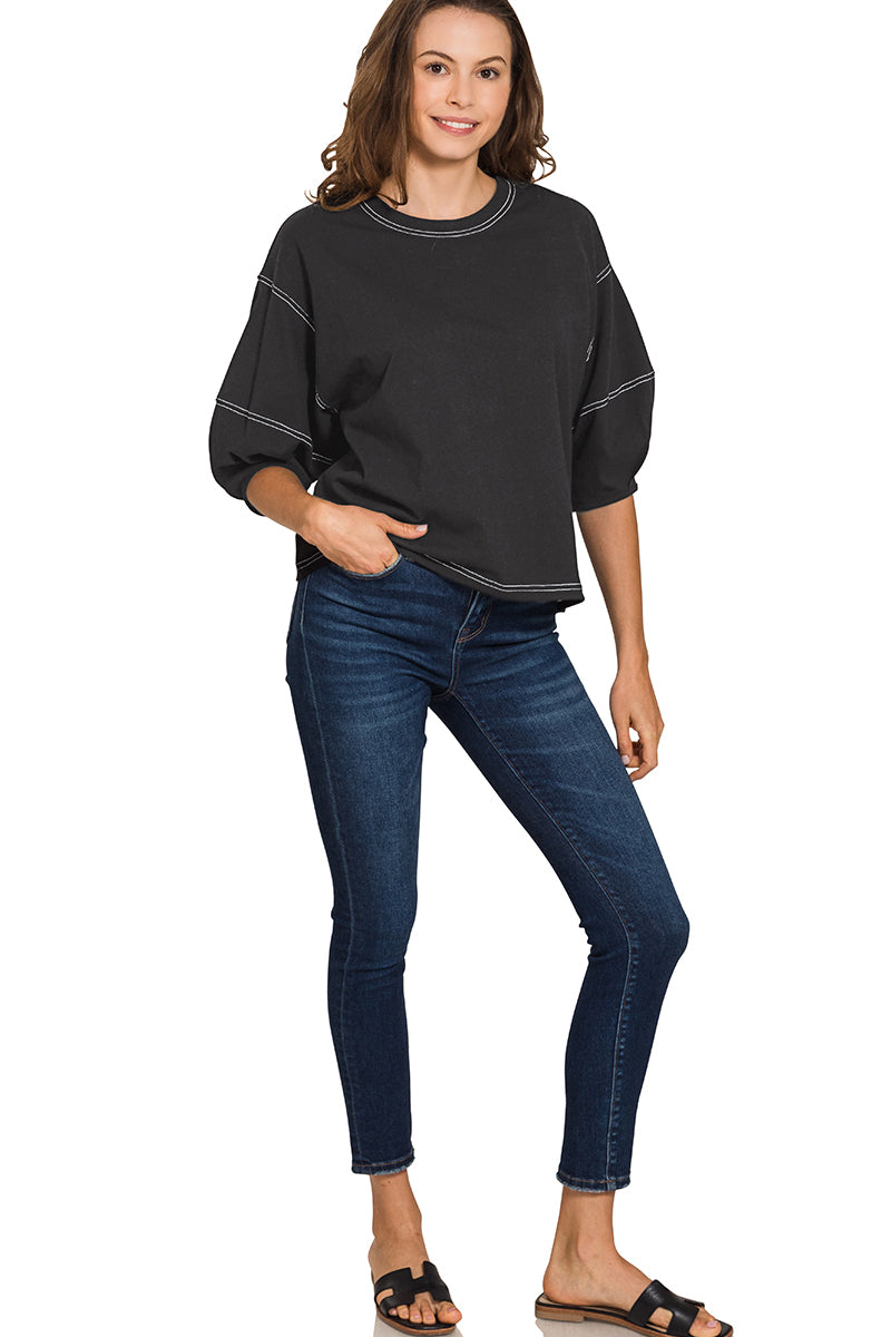 Woman wearing a black top and blue jeans on a white background