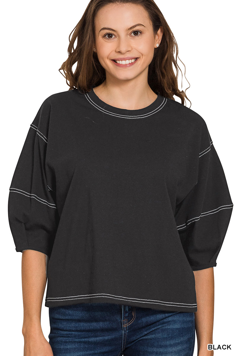 Woman wearing a black top with white trim on a white background
