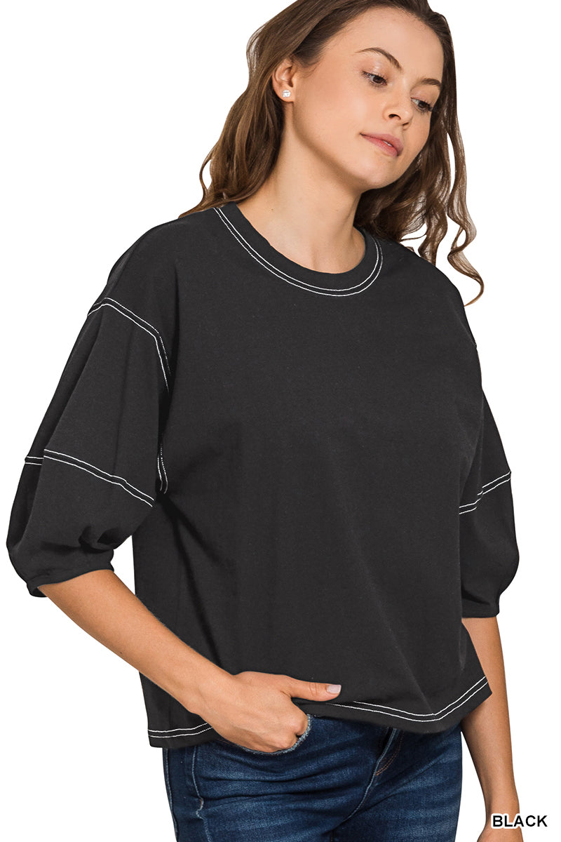 Woman wearing a black top with white trim on a white background