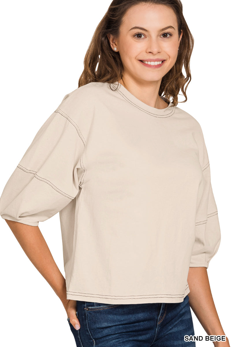 Woman wearing a sand beige top on a white background