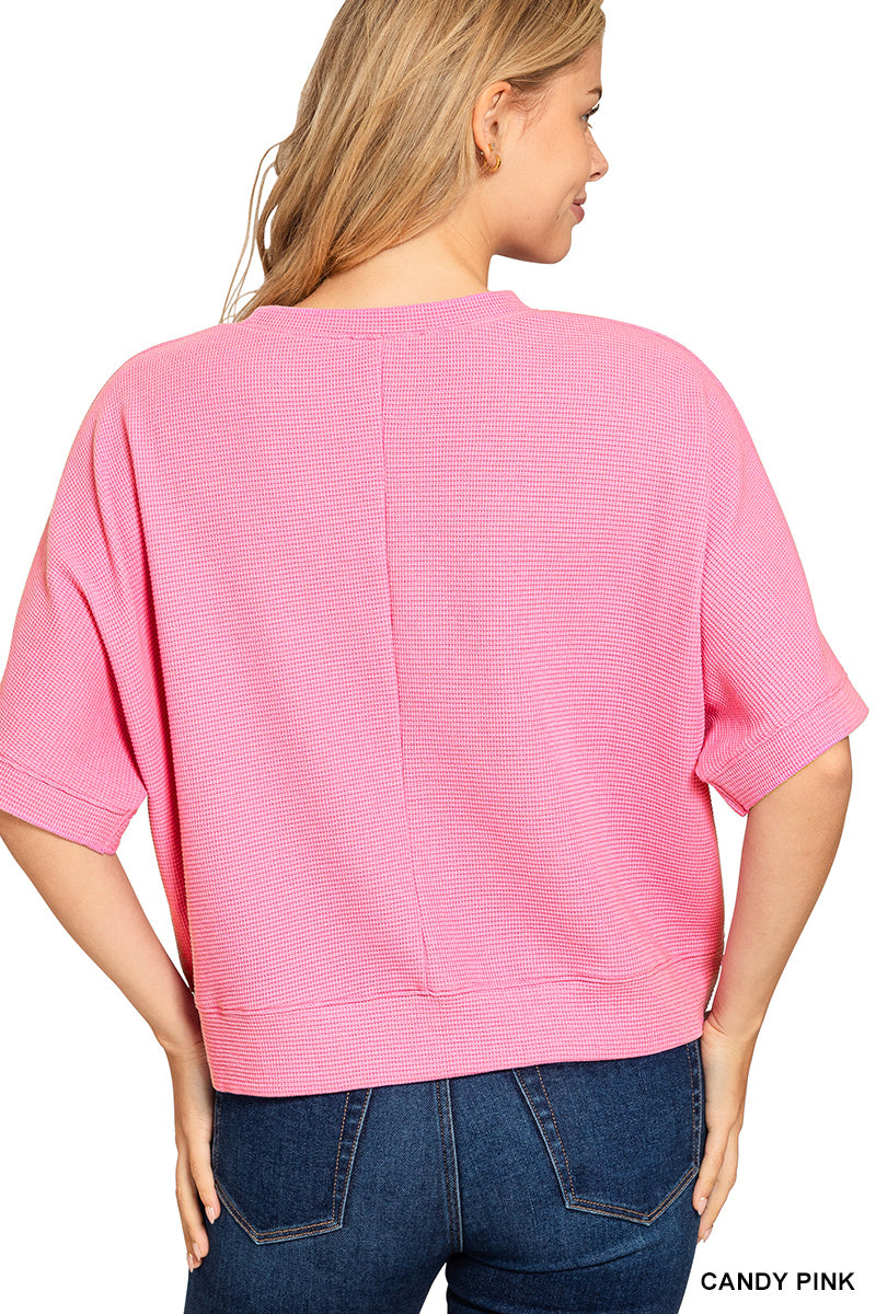 Woman wearing a pink textured top and blue jeans on a white background