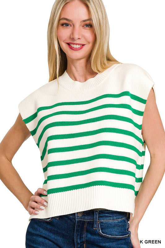 Woman wearing a white sleeveless sweater with green stripes and blue jeans on a white background