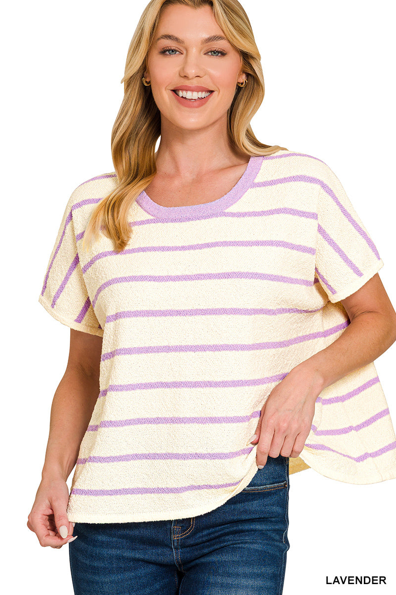 Woman wearing a ivory and lavender striped shirt with blue jeans on a white background