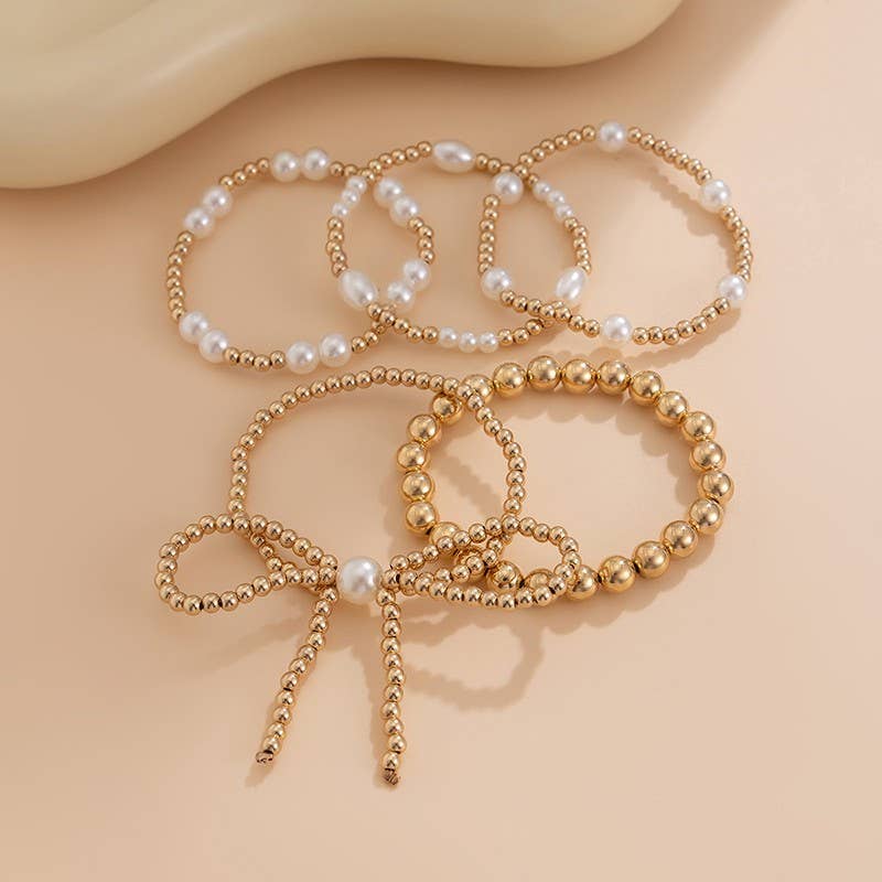 Gold and pearl bracelet set on a beige background