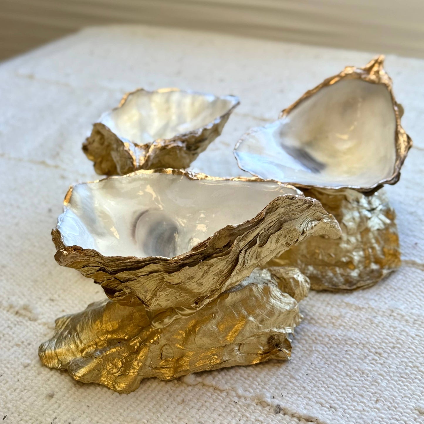 Gold-leafed oyster shell ring dish on a textured surface