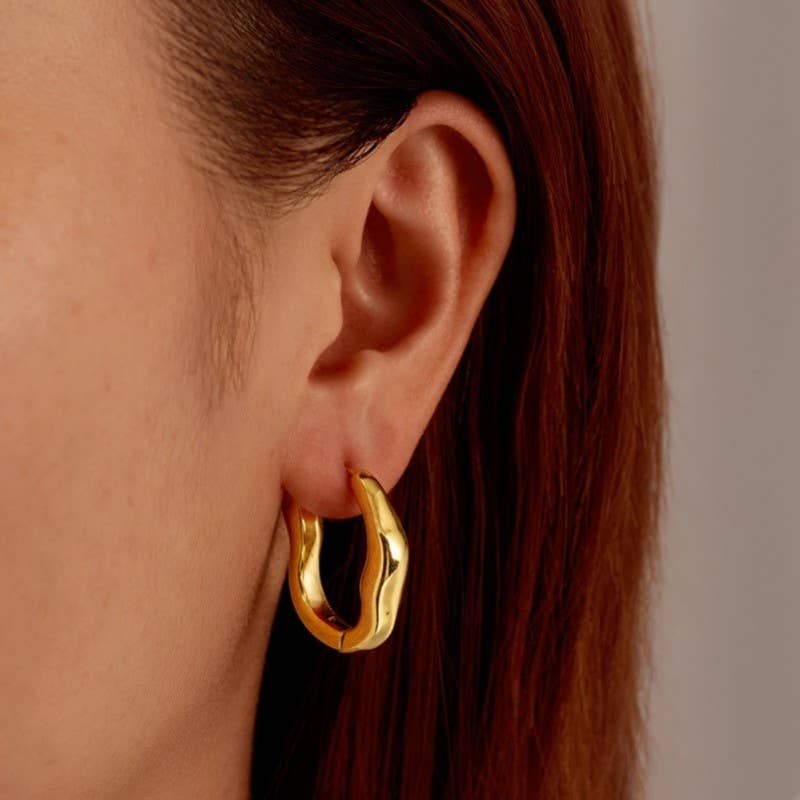 Gold hoop earring worn by a person with red hair.