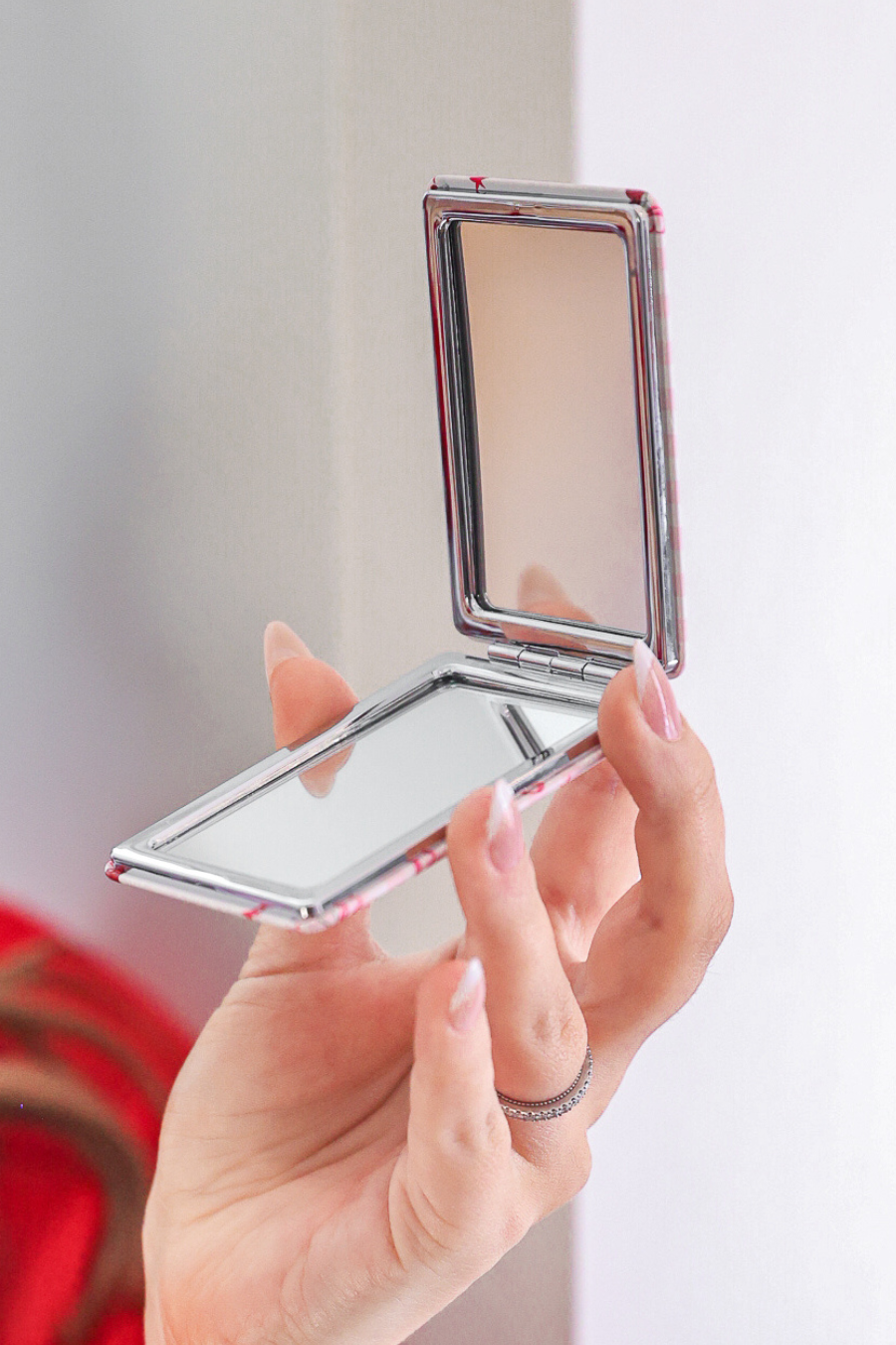 Compact mirror held by a hand with a blurred background